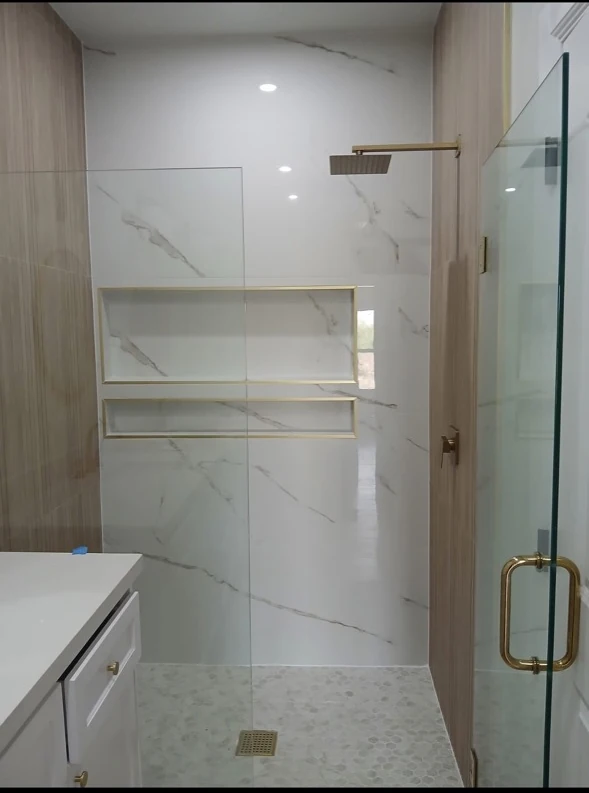 Light tiled shower with recessed niches and glass door.