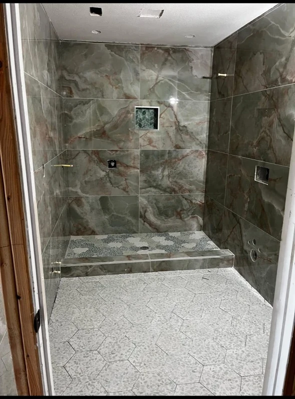 Shower with green stone tile and recessed niche.