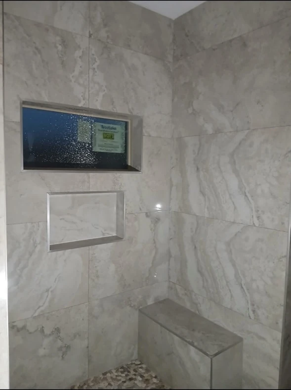 Bathroom wall with recessed niches and stone bench.