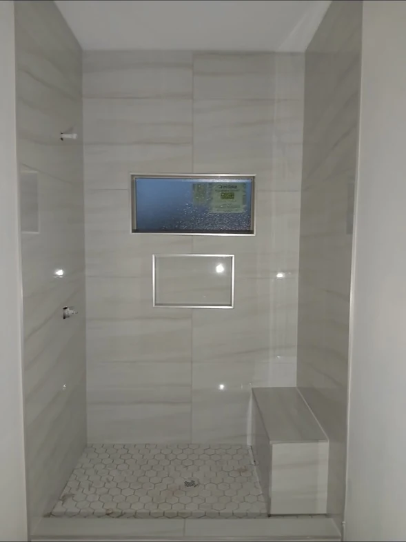 Light tile shower with niches and a bench.
