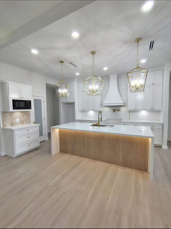 Kitchen with an island, white cabinetry, and wood-tone flooring.