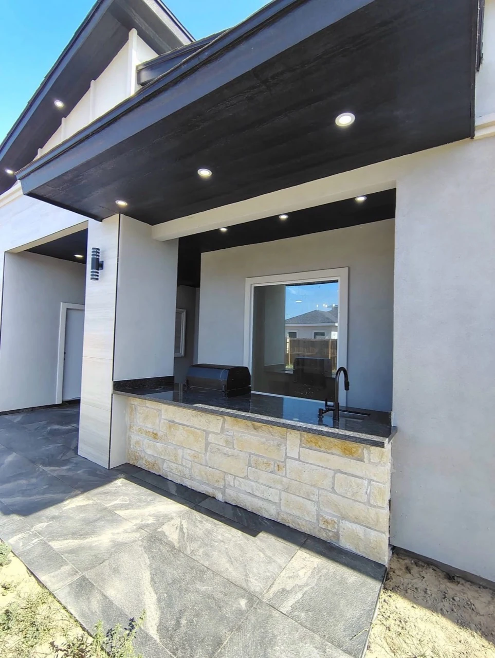 Covered outdoor kitchen with a stone counter.