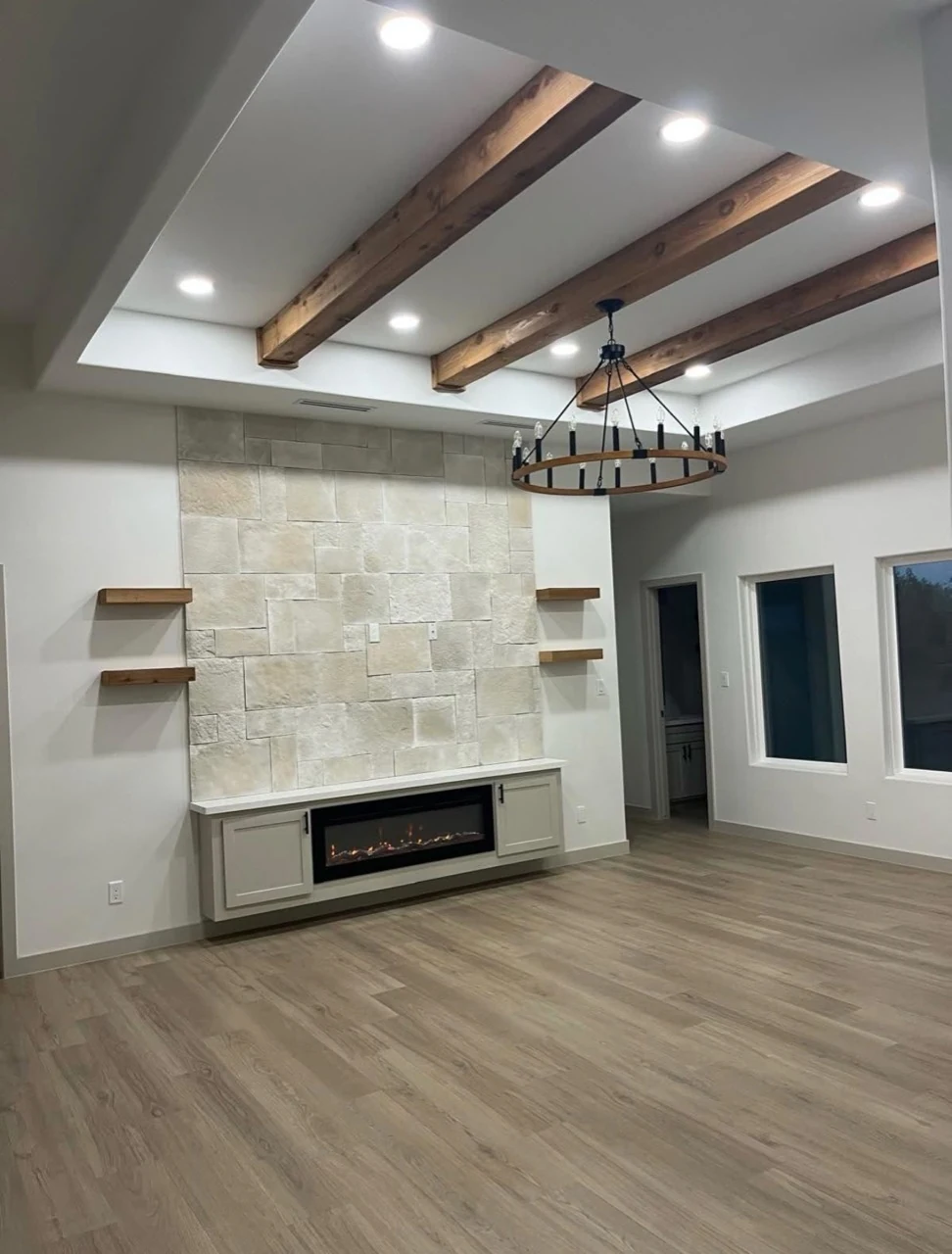 Living room with fireplace, shelving, and ceiling beams.